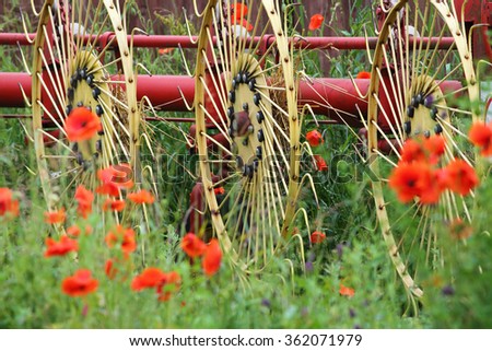 Old Farm device among flowers, especially poppies at organic farm where no pesticides are used.