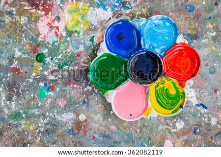 Photo of a artists palette loaded with various colour paints on the wood table background
