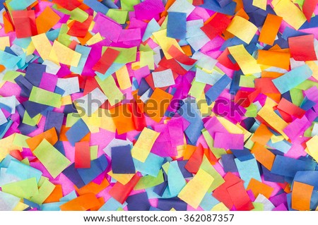 Brightly colored paper confetti background featuring red, yellow, blue, green, orange, and bright pink carnival colors