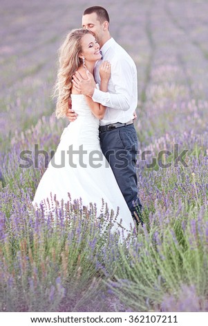 Young couple in love bride and groom, wedding day in summer. Enjoy a moment of happiness and love in a lavender field. Bride in a luxurious wedding dress. Summer mood and freedom.