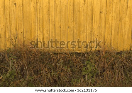 Old yellow wooden house and faded grass. Background.
