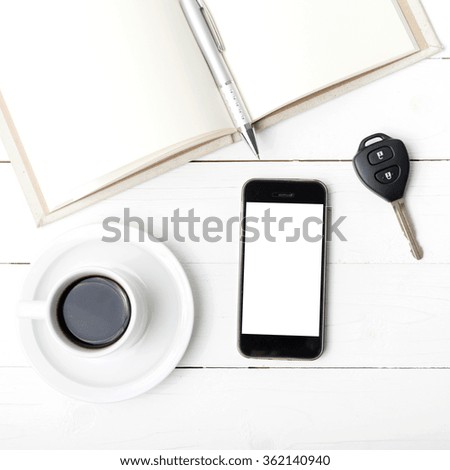 coffee cup with phone,car key and open notebook on white wood table