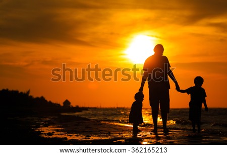 father and two kids walking at sunset