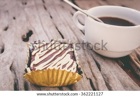 Piece of cake chocolate brownie and hot coffee on old wooden background. Shallow depth of field (dof), selective focus. Vintage picture style.