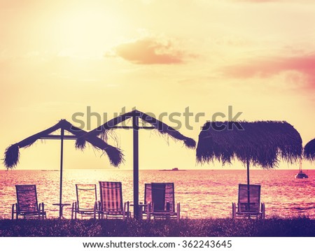 Vintage toned beach chairs and umbrellas at sunset, holidays background. 