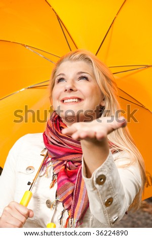 Picture of a young happy smiling girl standing under the rain with umbrella