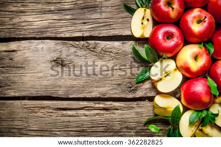 Fresh red apples with green leaves on wooden table. On wooden background. Free space for text . Top view