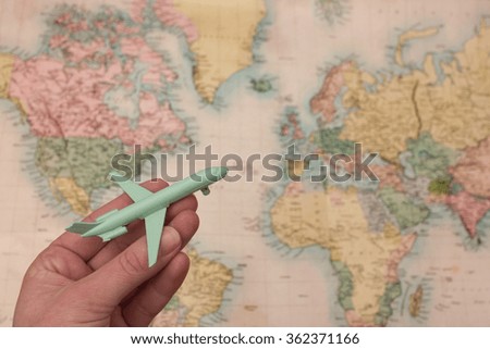 Wanderlust travel concept with hand holding airplane and blurred map background Royalty-Free Stock Photo #362371166