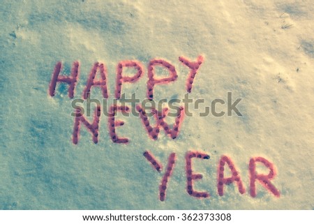 Happy New Year message on a snow field. Vintage filter applied.