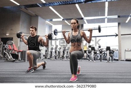 young man and woman training with barbell in gym
