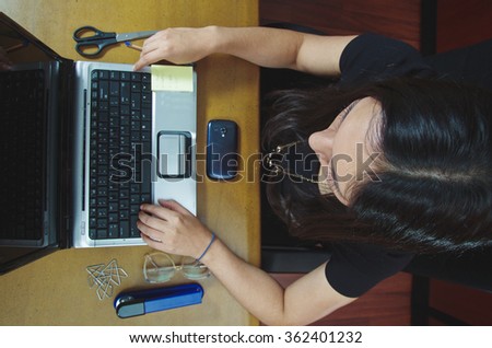 Hispanic brunette office woman working on laptop, shot from above angle