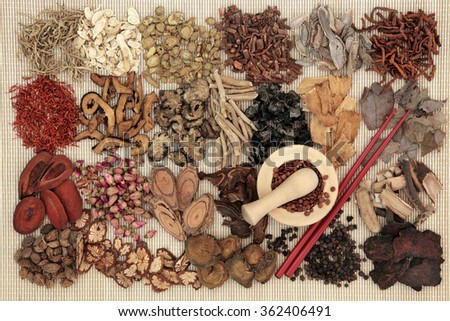 Traditional chinese herbal medicine ingredients over bamboo background with mortar and pestle and chopsticks.