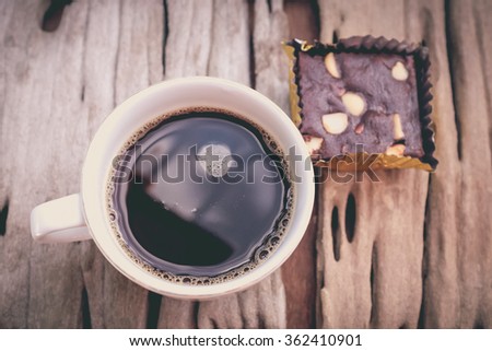 Top view. Piece of cake chocolate brownie and hot coffee on old wooden background. Shallow depth of field (dof), selective focus. Vintage picture style.