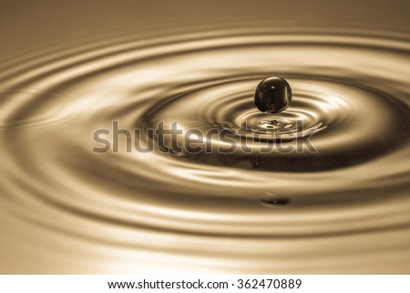 Black drop falls into the water and creates circles