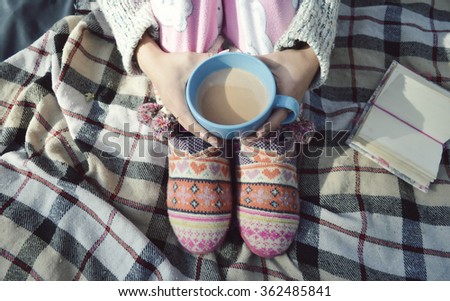 girl lying in bed reading a book, drinking cocoa
