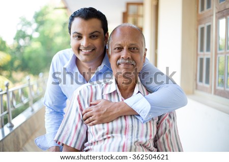Closeup portrait, family, young man in blue shirt holding older man in striped shirt from behind, happy isolated on outdoors outside balcony background Royalty-Free Stock Photo #362504621