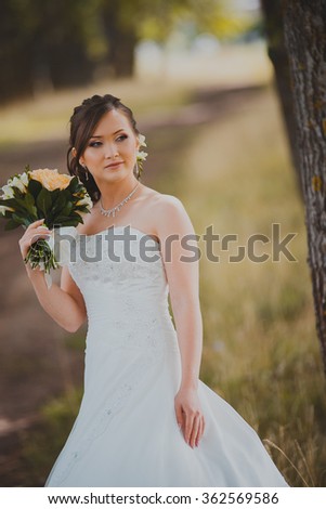 Beautiful bride in a luxurious white dress with a bouquet on the background of beautiful scenery