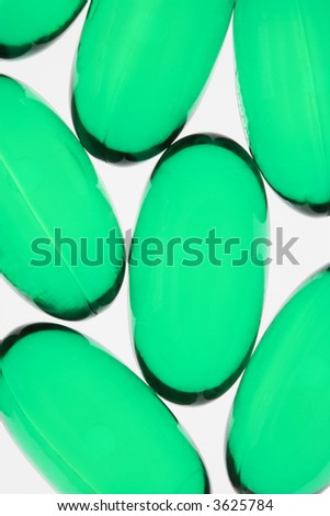 Close up of green capsule pills against white background.