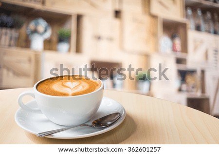 Hot art Latte Coffee in a cup on wooden table and Coffee shop blur background with bokeh image.