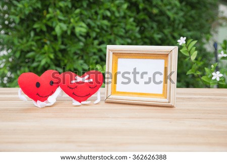 Doll red heart and picture frame on a wooden table, Valentine day concept.