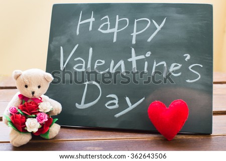 Valentine card with Teddy bear, heart on wooden black board with bow in vintage style.