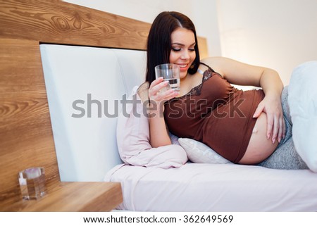 Beautiful pregnant woman drinking water to stay hydrated