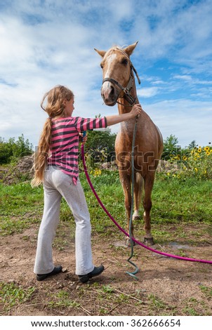 Girl washing a horse with a hose on a farm Royalty-Free Stock Photo #362666654