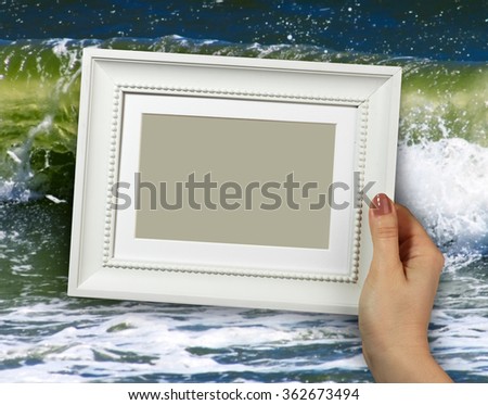 Wooden frame in beautiful woman hands on the background sea waves on beaches, sands, foam