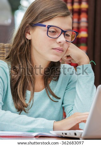 pretty student girl doing homework at home with a laptop