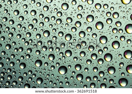 Water drops on transparent green glass surface.