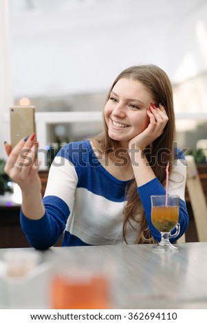 Woman take self picture on her phone in light cafe