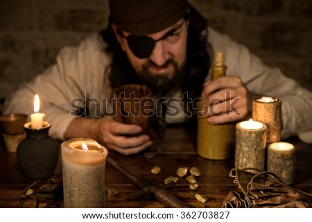 grumpy pirate with a bottle of rum sitting on a medieval table with a lot of candles