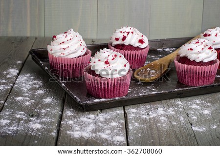 Freshly Baked creamy Red Velvet Cupcakes in a baking tray. Tastefully displayed on rough wooden slats.