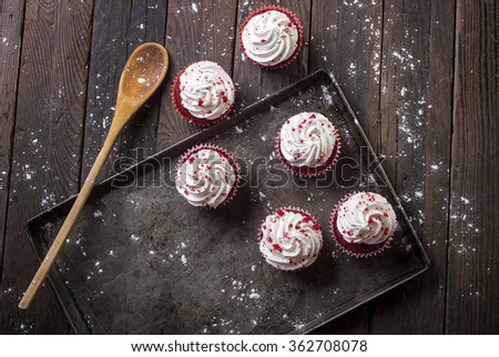 Freshly Baked creamy Red Velvet Cupcakes in a baking tray. Tastefully displayed on rough wooden slats.