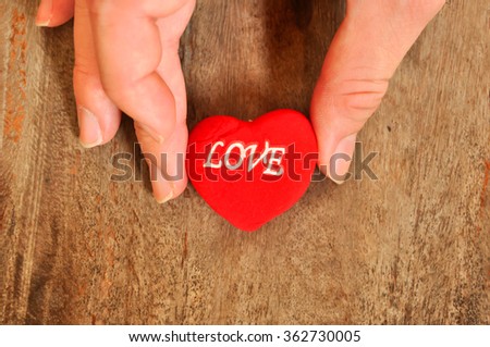 Heart with "LOVE" word and hand pasted on old table for giving to someone in valentine event