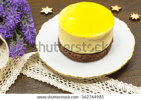 Round yellow cake on white saucer. Bands and lavender on the table. Icons of stars