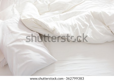 Top view of an unmade bed with crumpled bed sheet, a blanket and pillows after waking up in the morning. Royalty-Free Stock Photo #362799383