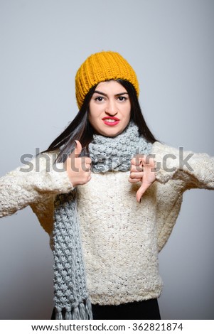 Eastern brunette girl showing thumbs down badly, hipster in winter clothes, isolated studio portrait emotions