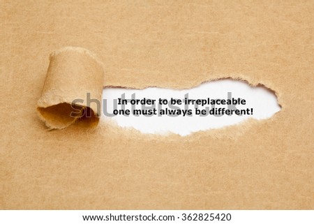 The motivational quote In order to be irreplaceable one must always be different, appearing behind torn paper. Royalty-Free Stock Photo #362825420