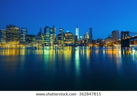 New York City Manhattan midtown at dusk with skyscrapers illuminated over east river