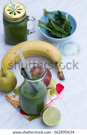 Fresh homemade green smoothie with spinach, lime, apple and banana - healthy way to start your day. Detox and dieting. Natural light, selective focus. White table. 