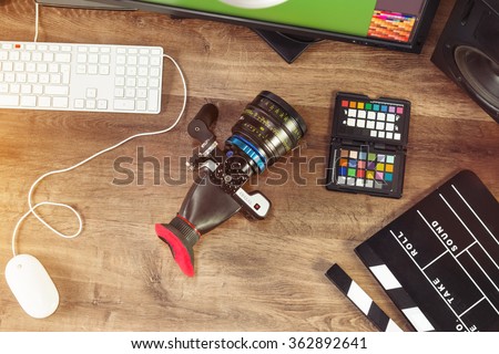 Desktop shot of a modern digital Cinema Camera and clapboard on stylish wooden desktop workplace / Background