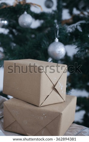 boxes in craft paper near new year tree with white and silver balls