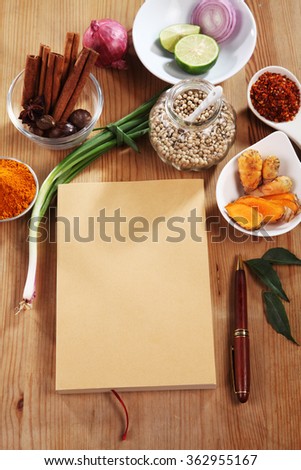blank brown cover book with spices on a wooden surface 