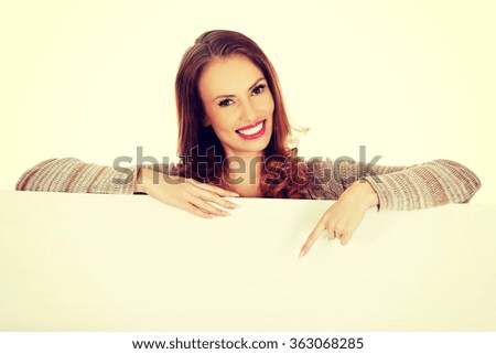 Happy woman pointing on blank board.