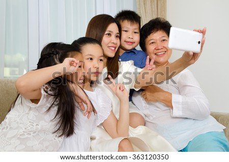Asian three generations family taking photo of themselves using handphone