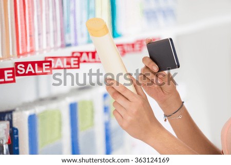 Cropped image of female customer photographing cosmetic product in supermarket