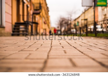 Streets in the late autumn, pedestrians walk on the sidewalk. The view from the sidewalk level