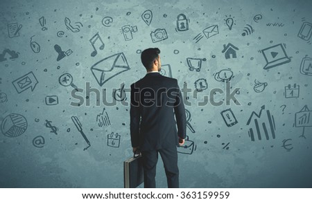 Businessman drawing a media icons on a wall