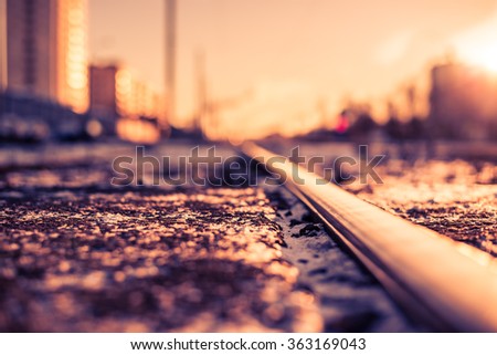 Bright winter sun in a big city, railroad tracks. View from the level of the snow-covered land, image in the orange-blue toning